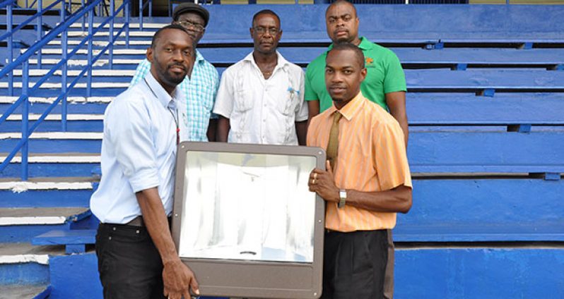 ILLUMINATION! Director of Sport Christopher Jones (left) hands over one of 15 flood lamps that will be erected at the MSC ground to Regional Executive Officer of Region 10, Gavin Clarke, yesterday while in background from left, Colin Boyce, MSC president, Avery Trim and Edison Jefford share the moment in Linden.