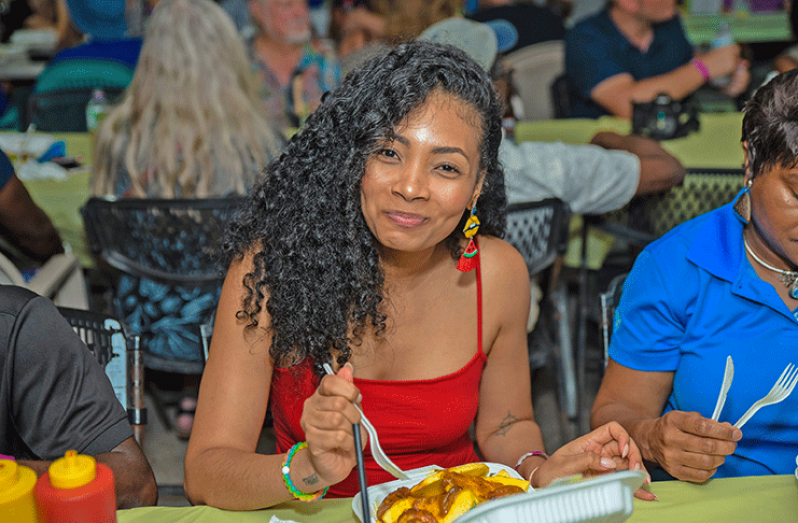 Guyana’s very own songstress, Timeka Marshall taking a bite during the opening event at Oistin (Dwayne Carter photo)