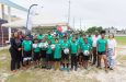 Deputy Chief of Mission at the U.S. Embassy Guyana, Adrienne Galanek (far right), 2nd Vice President of the GFF, Rawlston Adams (third from right), and Y-RIE Country Director Tiffany Daniels (left) pose with other representatives from GFF and Y-RIE, alongside youth community footballers