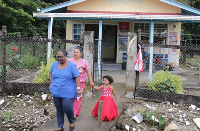 Pretty Debideen walks out of the island’s health centre with her young daughter and a tourist
