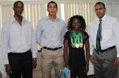 North, Central American and Caribbean World Masters Athletics Championships triple gold medal winner Alicia Fortune (2nd right), strikes a pose with Minister of Sport Dr Frank Anthony (right) Permanent Secretary Alfred King (left) and an executive of the Guyana Masters Association.