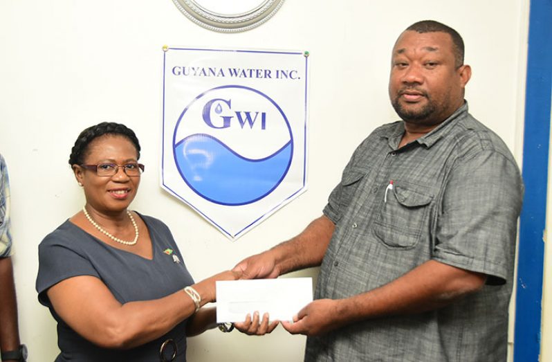 GWI Director of Human Resources Management and Development, Gale Doris, hands over the sponsorship cheque to Hilbert Foster.