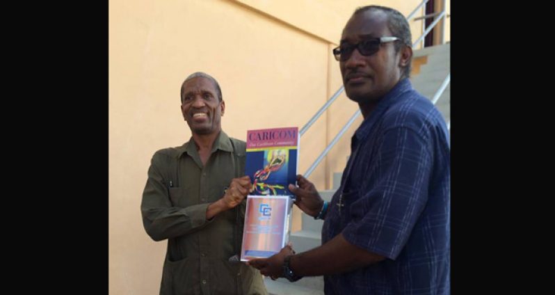 CARICOM Assistant Secretary General and Director of Human and Social Development, Dr Douglas Slater hands over several pieces of literature to St Francis Community Developers President Alex Foster during his visit to the NGO