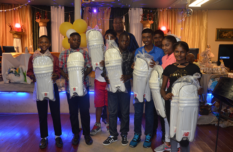 RHTYSC’s Secretary/CEO Hilbert Foster poses with young cricketers after presenting them with a pair of batting pads each.