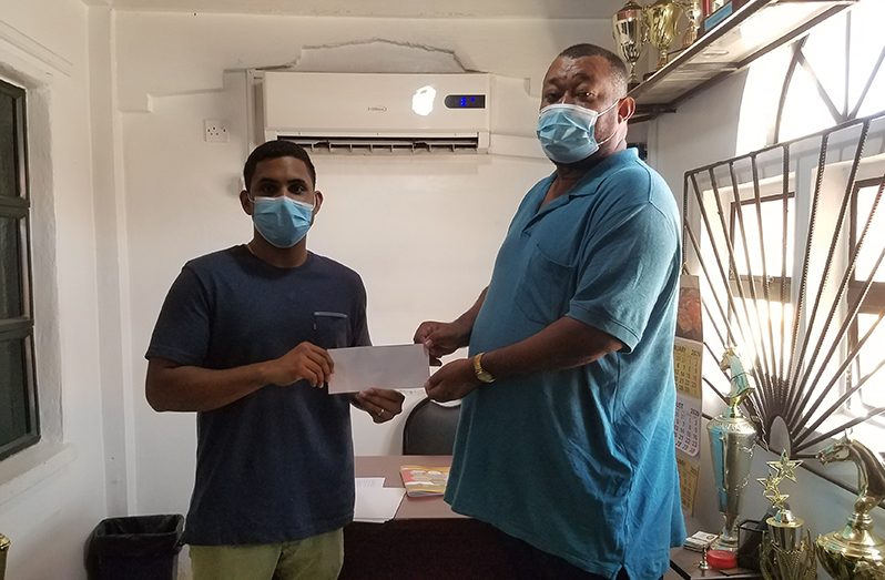 BCB president Hilbert Foster receives sponsorship from Nand Persaud marketing executive Devesh Persaud.