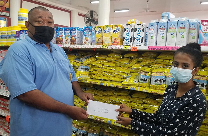 A representative of J. Supermarket hands over sponsorship to BCB president Hilbert Foster.