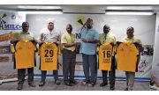 RHTYSC Secretary Hilbert Foster receives the coloured uniform from NAMILCO Managing Director Bert Sukhai in the presence of other company executives