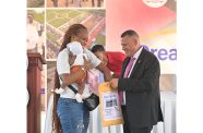 A mother holding her child pulls her lot number from an envelope being held by Minister of Housing and Water, Collin Croal, at the two-day 'Dream Realised' Housing Drive at the State House, Region Six