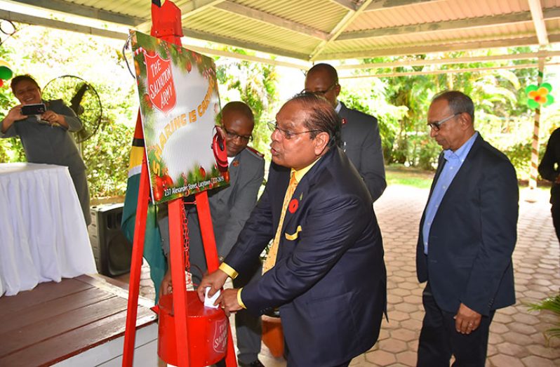 Here’s mine, you join too: Prime Minister Moses Nagamootoo gets the ball rolling with a deposit in the kettle at the annual
launch of the Salvation Army’s Christmas Kettles Appeal at the Georgetown Club on Friday (Samuel Maughn Photo)