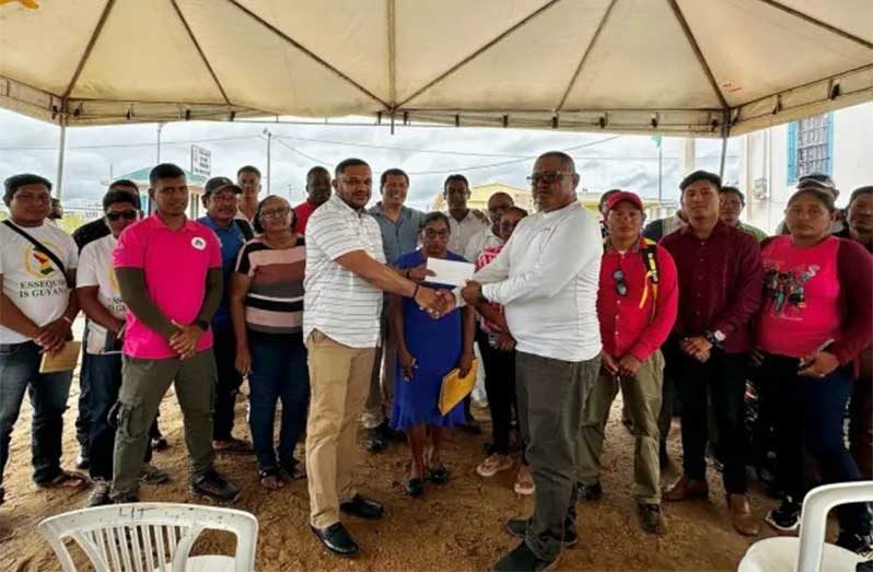 Minister of Natural Resources, Vickram Bharrat, handing over funds to one of the village leaders in Region Nine