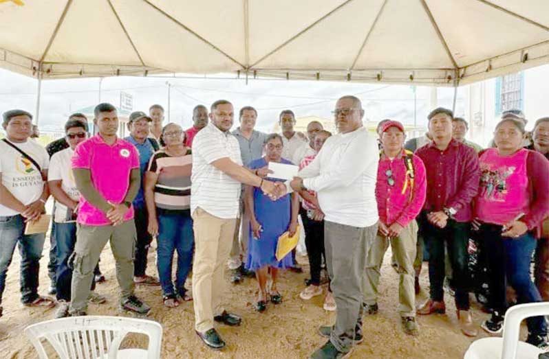 Minister of Natural Resources, Vickram Bharrat, handing over funds to one of the village leaders in Region Nine