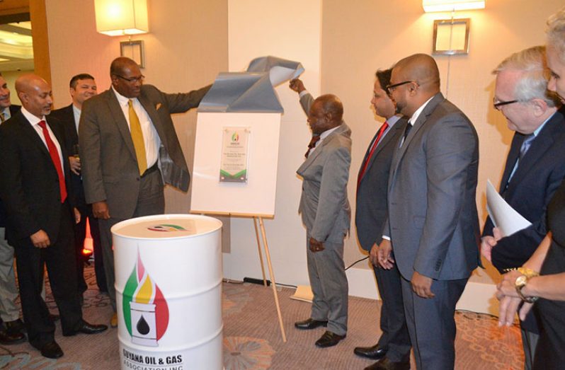 Minister of Foreign Affairs  Carl Greenidge and Attorney-at-law Nigel Hughes officially unveil the plaque marking  commissioning of the Guyana Oil and Gas Association  as other members of the body look on