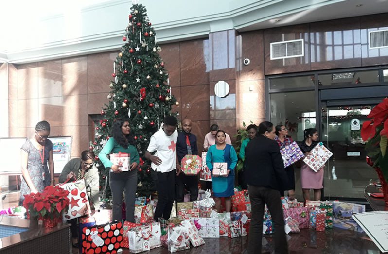 Staffers at the Guyana Bank of Industry and Commerce (GBTI) display some of the 130 gifts collected as a result of the Red Cross `Wreath of Smiles’ project