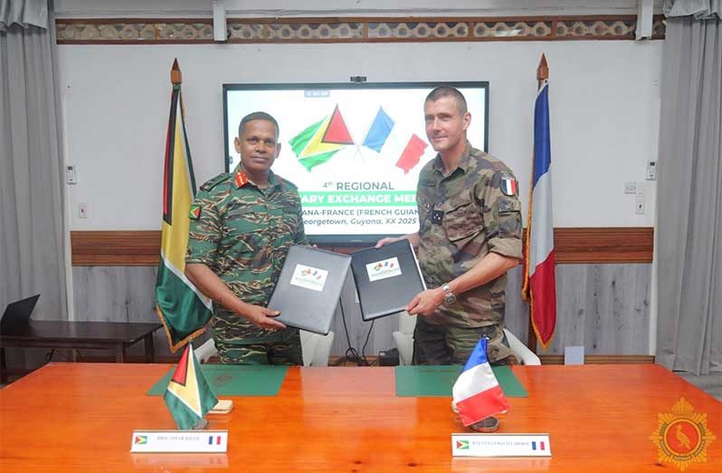 Chief of Defence Staff Brigadier Omar Khan, MSS, and Major General Géraud Laborie, Commander of the French Armed Forces in French Guiana, exchange documents during the 4th Regional Military Exchange Meeting between Guyana and France, held in Georgetown on Wednesday