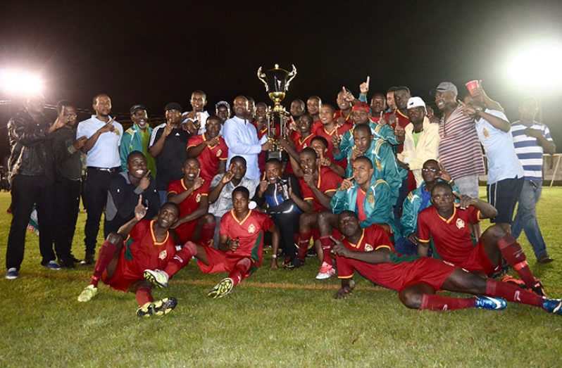 GFF President Wayne Forde hands over Elite League Leaders' trophy to captain Eusi Phillips surrounded by happy team mates and supporters.