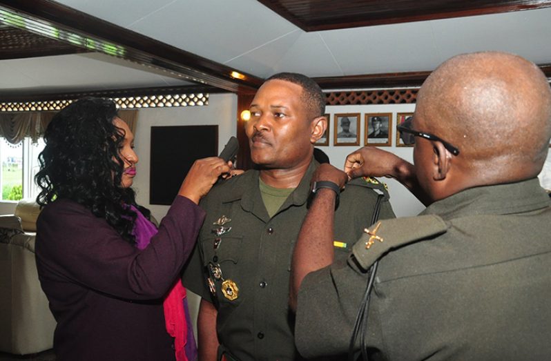 Substantive Colonel Trevor Bowman being decorated with his new badge of rank by Chief-of-Staff, Brigadier Patrick West and his wife Mrs Gee-Gee Bowman