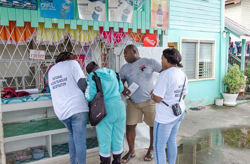 A resident of Tucville, Carl Benjamin, being assisted by GECOM staff to get registered during the house-to-house registration process (Delano Williams photo)