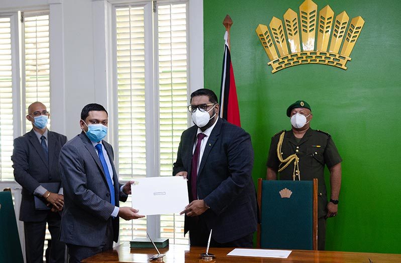 Newly-appointed GECOM Commissioner, Attorney-at-law Manoj Narayan, receives his instrument of appointment from President Irfaan Ali at State House (Delano Williams photo)