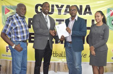 GFF president Wayne Forde (second from right) presents the new FIFA-approved Disciplinary Code to the Chairman of the GFF’s Disciplinary Committee, Roger Yearwood.