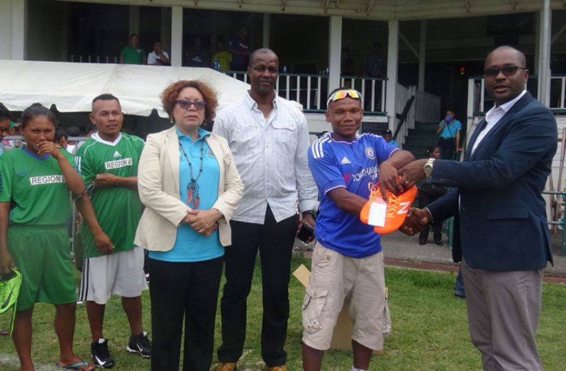 GFF president Wayne Forde makes the presentation of football cleats to a player at the Indigenous Heritage Sports.