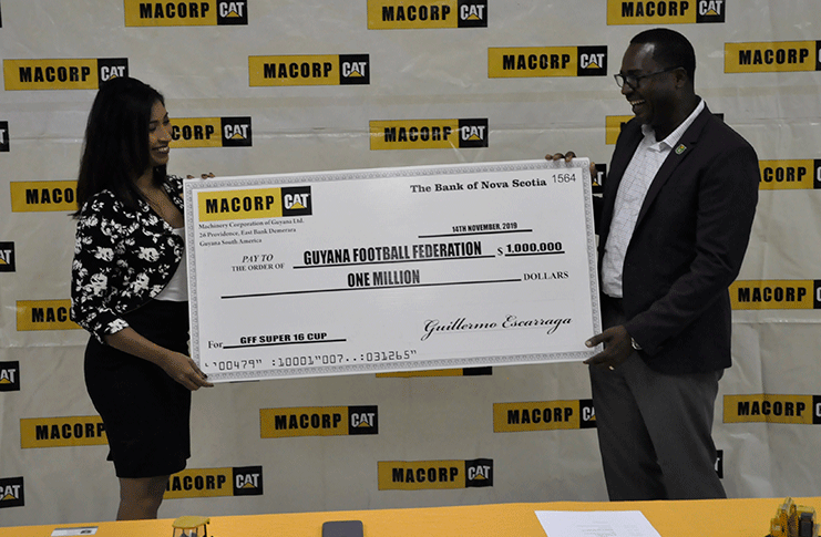 Chief Financial Officer Human Resources Manager of MACORP, Mrs Anita Ramprasad, and GFF president Wayne Forde hold up the ceremonial cheque during the presentation.