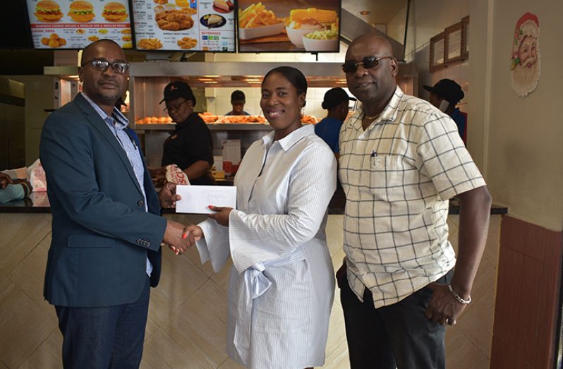 Camex Restaurants Marketing Consultant, Deslyn Griffith, presents cheque to GFF president Wayne Forde. Also in photo is co-director of the Kashif and Shanghai Organisation, Aubrey Major.