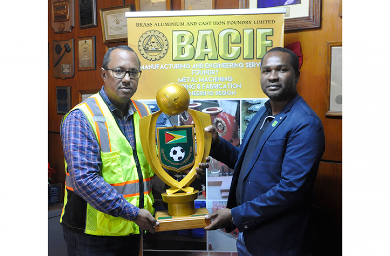 GFF president Wayne Forde accepts the GFF Super 16 Cup trophy from BACIF’s Managing Director, Peter Pompey.