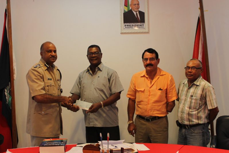 Acting Commissioner Seelall Persaud receives the $1M cheque from Mr. Patrick Harding, while Messrs. Charles Da Silva and Dabria Marcus (left to right) look on