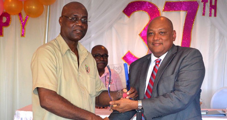 Gordon Nestor, Manager, Geological Services Division, receives his long-service award for 30 years of service to the GGMC from Minister Raphael Trotman.