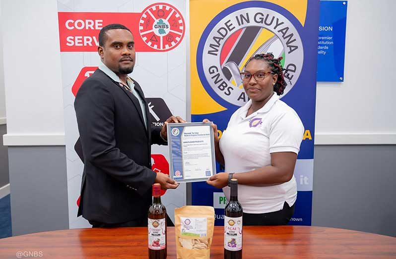 GNBS Head of Certification Services (ag), Keon Rankin, hands over the certificate to Managing Director of Sand Flower Products, Xuxa Lowe