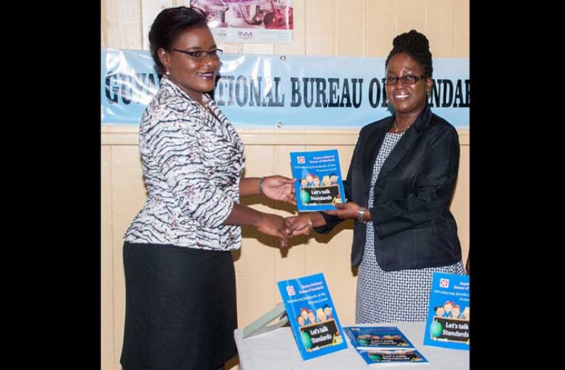 Technical Officer of the Education Ministry, Tameka Barker ( at left) receives a copy of the booklet from GNBS Executive Director, Candelle Walcott-Bostwick. (Delano Williams Photo)