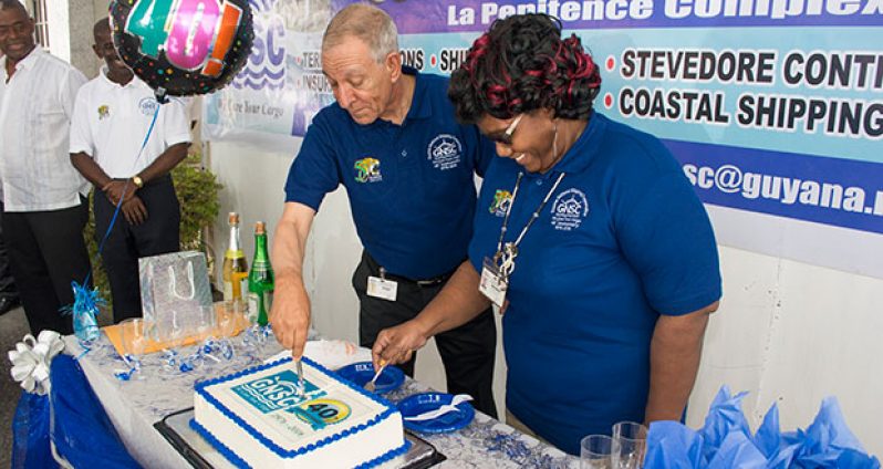 Long-standing employees of GNSC, Eion Oudkerk and Yvonne Sandiford, cutting the anniversary cake at the Corporation’s Lombard Street, Georgetown location