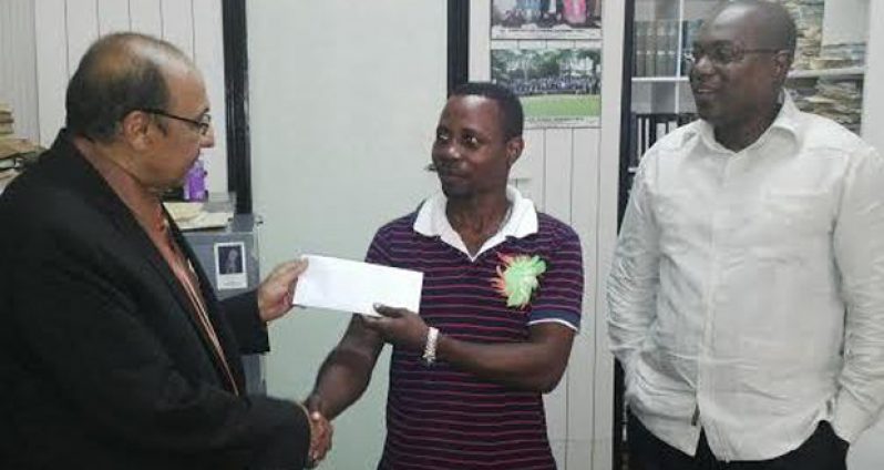 GOA President KA Juman Yassin makes the presentation to coach Sebert Blake while GBA President Steve Ninvalle looks on.