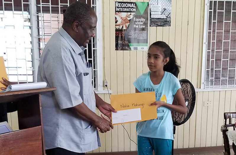 President of the Guyana Public Service Union (GPSU), Patrick Yarde, presents Nalia Mahangi with an award. Mahangi gained a spot at the St. Joseph High School