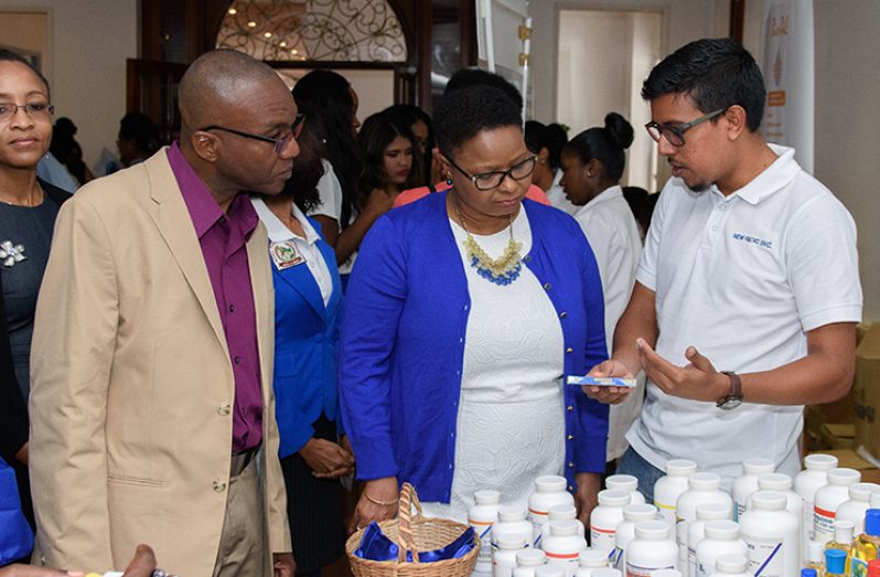 Public Health Minister Volda Lawrence and Director of Pharmacies at the Public Health Ministry Oneil Atkins, listen as a pharmacist speaks on the Whizz Aspirin-free medication at one of several booths (Samuel Maughn photo)