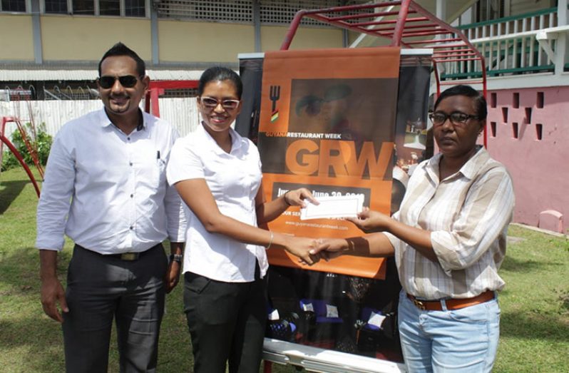 Caregiver of the St. Ann’s Orphanage, Sharon Munro (right) receives a voucher from a representative of the Herdmanston Lodge and President of the Tourism and Hospitality Association of Guyana(THAG), Mitra Ramkumar (left)