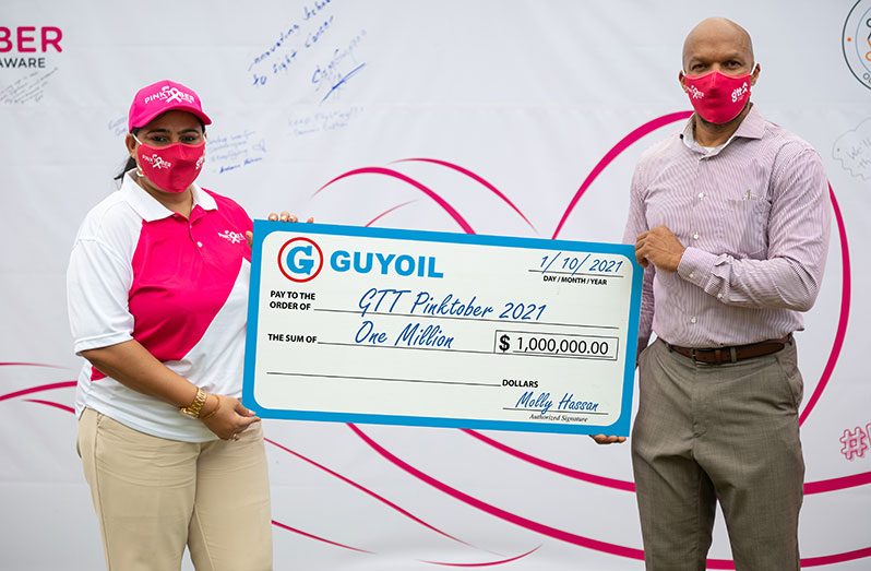 Marketing Executive at GUYOIL, Mowshani Lekraj, hands over a replica of the $1M Pinktober cheque to GTT’s Chief Operations Officer, Orson Ferguson