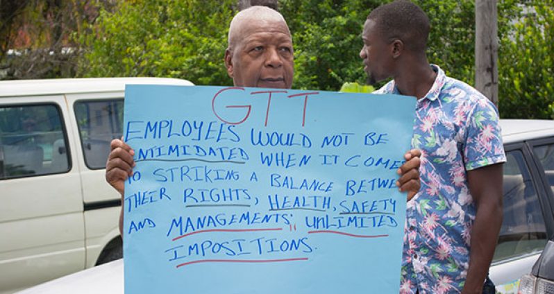 A GT&T employee holds up a placard, which sums up workers’ concerns