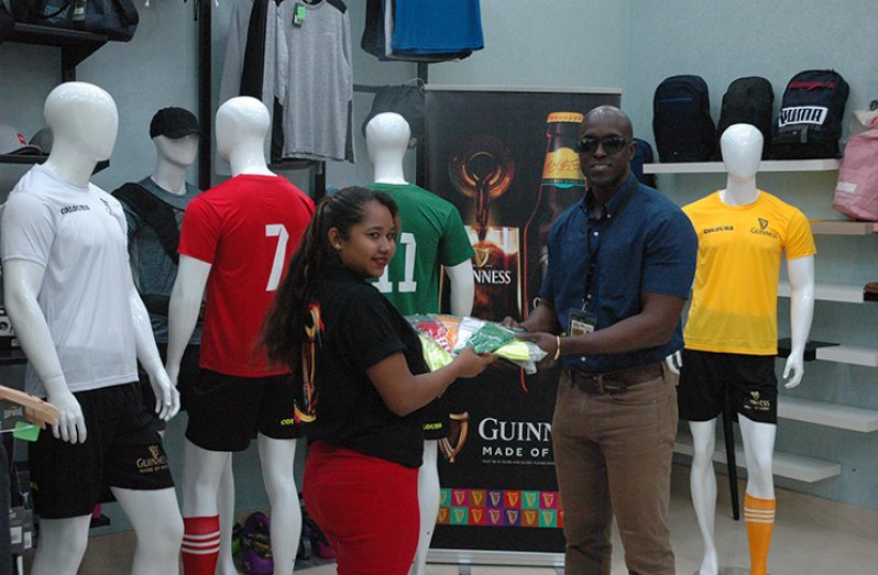 Guinness Brand executive Lee Baptiste (right) receives the branded kits from Colours Boutique representative, Marissa Williams.