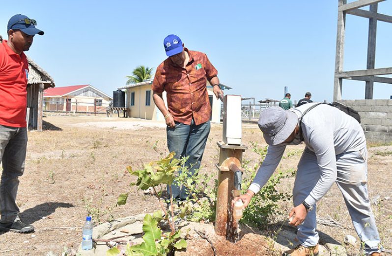 A water sample being taken for analysis as GWI Managing Director Dr. Richard Van West-Charles (center) watches on