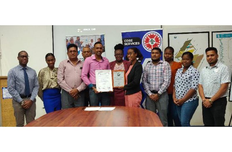 GWI's Head of Water Quality (ag), Avinash Parsram and Laboratory Quality Officer, Angela Fordyce, surrounded by GWI & GNBS staff, display the certificate and plaque presented to them by GNBS 
