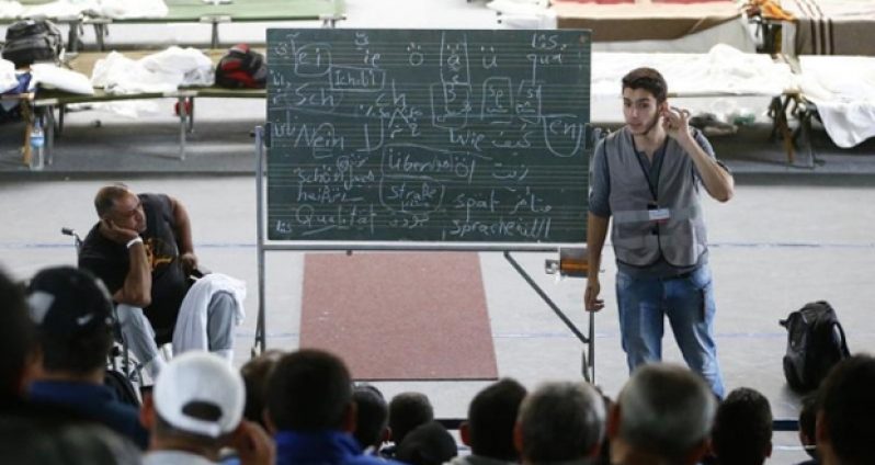 A volunteer conducts German language lessons for Arabic-speaking migrants inside an improvised shelter at a sports hall in Hanau, Germany.