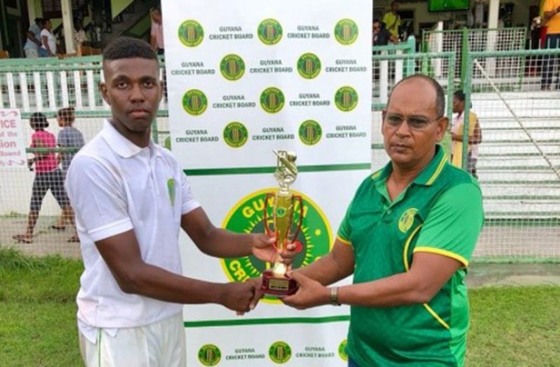 Seon Glasgow collects his man-of-the-match trophy from chairman of Junior Selection Panel Mr Nazimul Drepaul.
