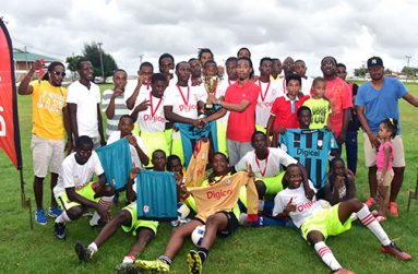 Winners Sir Leon’s Lessons pose while their captain collects their trophy from Digicel representative Yancey Haywood