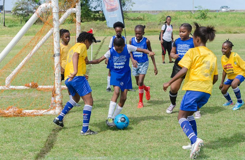 A player uses her skill to evade defenders in yesterday’s opening round of the Smalta Girls Schools football Tournament (Delano Williams Photo)