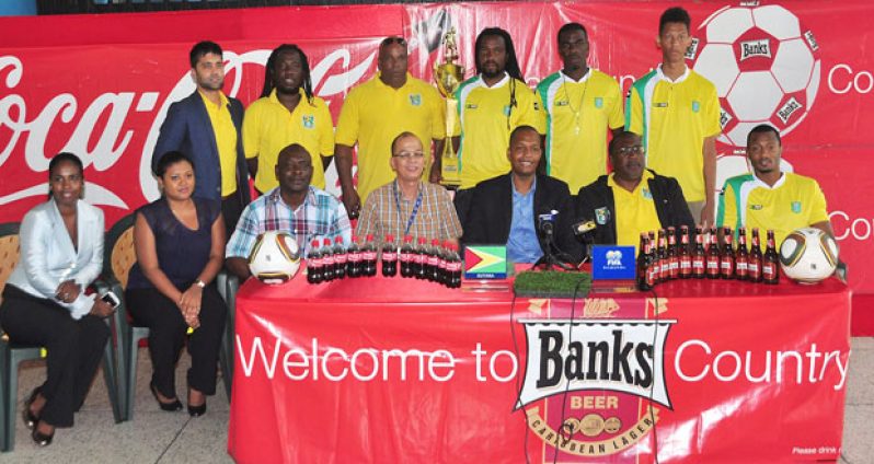 Officials of both Banks DIH and the Guyana Football Federation (GFF) are joined by some of the members of the ‘Golden Jaguars’ at Thirst Park yesterday.
