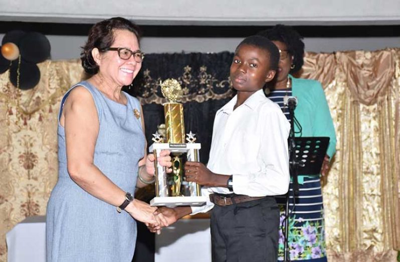 First Lady, Mrs. Sandra Granger presents Mr. Joshua Abrams with the trophy for the Most Improved Student, at the graduation ceremony.