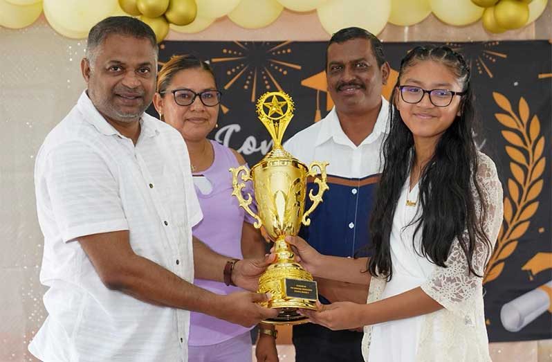 Minister within the Ministry of Public Works Deodat Indar hands over a trophy to the school’s top performers while encouraging others to remain focused on their education