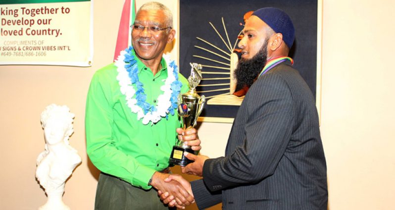 President David Granger (right) presents the award to West Indies Test player Assad Fudadin.