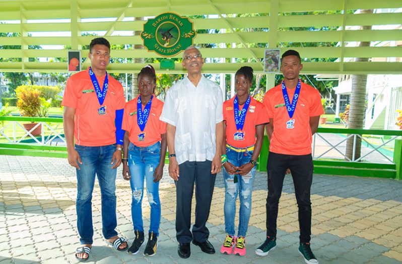 President David Granger is flanked by Guyana’s CARIFTA Games medal winners, (L-R) Compton Caesar, Claudrice McKoy, Chantoba Bright and Anfernee Headecker. (Delano Williams photo)